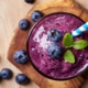 Glass of blueberry smoothie on wooden background from top view