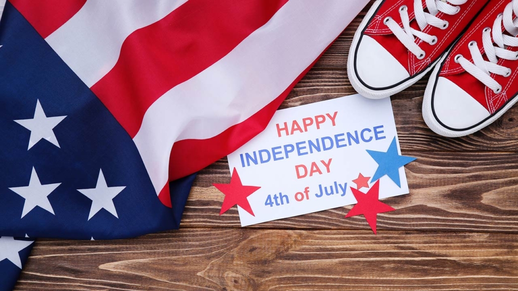 Happy Independence Day with flag and pair of shoes on wooden background