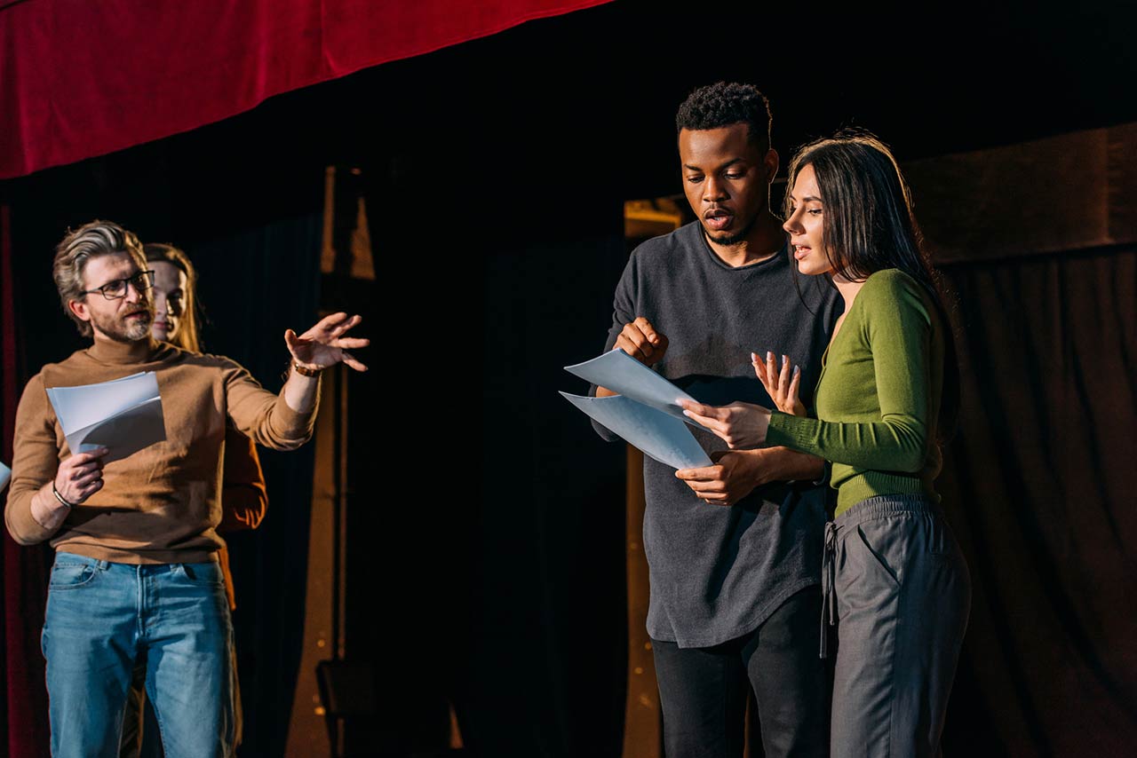 Theater director, multicultural actors and actress rehearsing on stage