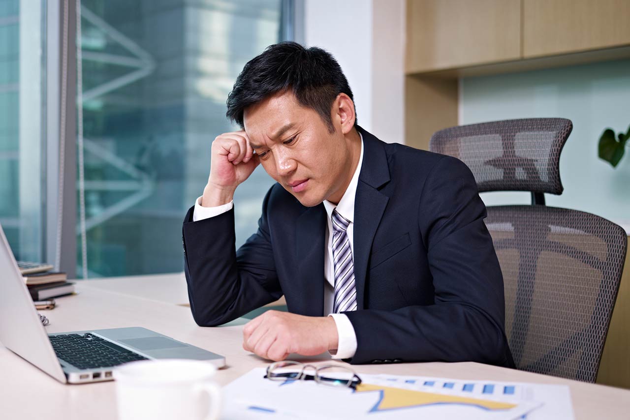 Asian businessman sitting and thinking in office, looking frustrated